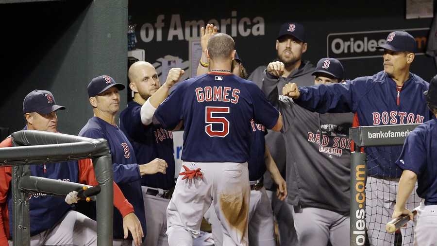 Boston Red Sox Jonny Gomes is greeted by teammates in the dugout after scoring on a single by David Ross in the fourth inning of a baseball game against the Baltimore Orioles, Sept. 28, 2013, in Baltimore. 