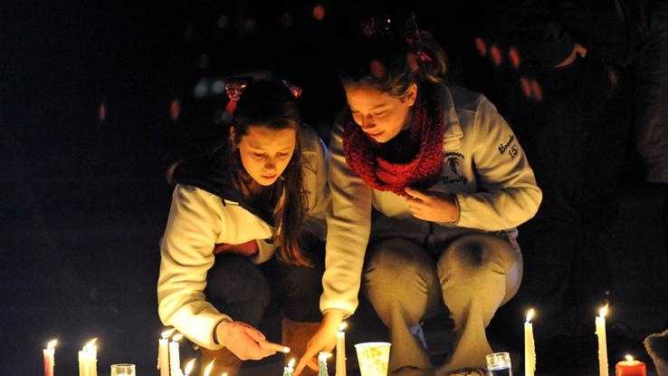 Danvers High School students Emma Gamble, left, sophomore, and Brooke Baracewicz, right, junior, light a candle at a memorial outside the high school during a candle light vigil held for Danvers High School math teacher Colleen Ritzer who was murdered by one of her students, 14 year old Philip D. Chism.
