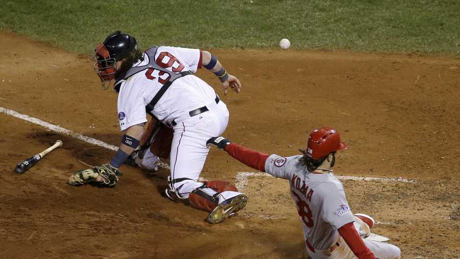 St. Louis Cardinals' Pete Kozma scores on a sacrifice fly as Boston Red Sox catcher Jarrod Saltalamacchia can't handle the throw during the seventh inning of Game 2 of baseball's World Series Thursday, Oct. 24, 2013, in Boston. 