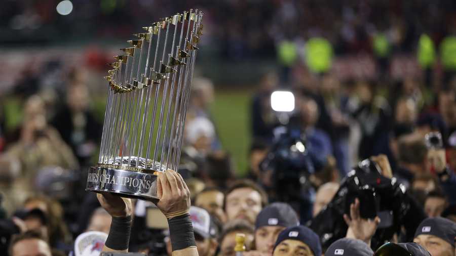 A player holds up the championship trophy after defeating the St. Louis Cardinals in Game 6 of baseball's World Series Wednesday, Oct. 30, 2013, in Boston. The Red Sox won 6-1 to win the series. 