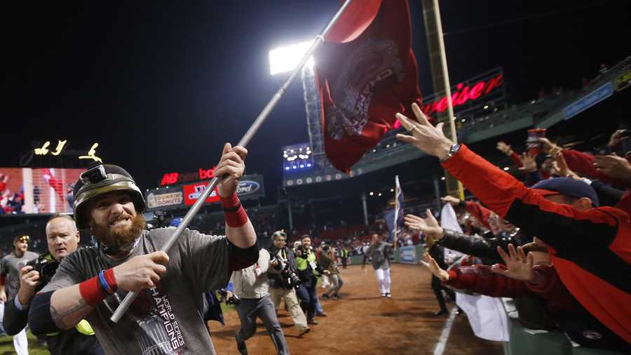 Boston Red Sox left fielder Jonny Gomes runs with a championship flag after defeating the St. Louis Cardinals in Game 6 of baseball's World Series Thursday, Oct. 31, 2013, in Boston. The Red Sox won 6-1 to win the series. 
