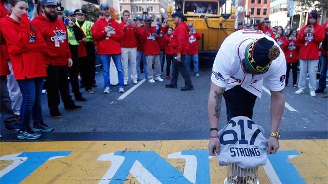 Boston Red Sox's Jonny Gomes places the championship trophy and a Red Sox baseball jersey at the Boston Marathon Finish Line during the rolling on Nov. 2, 2013, to remember those affected by the Marathon bombing.