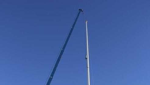 A replacement 110-foot flagpole is slowly hoisted into the air by a crane at Toyota of Braintree on Saturday, Nov. 9, 2013.