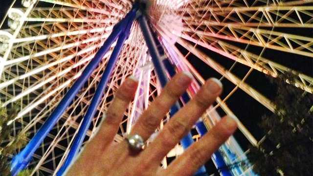 Kristina D'Agostino holds her engagement ring in front of the carousel in Lyon, France