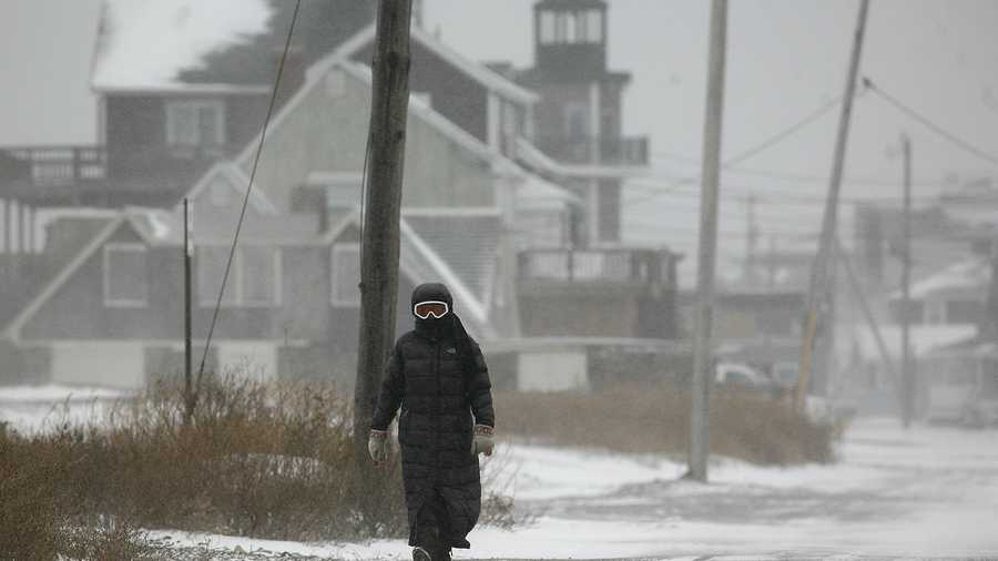 A woman with goggles walks along Turner Road in Scituate, high winds pushed sea spray hard, making it hard to see without eye protection.