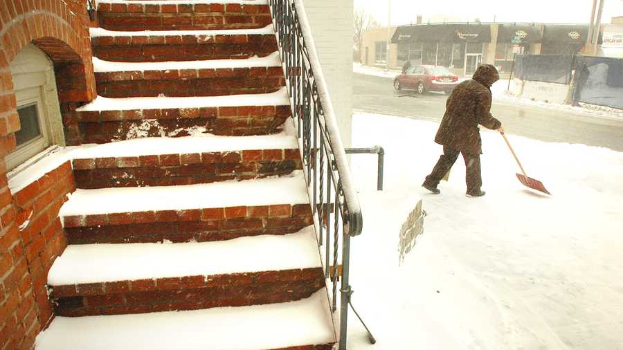 Joe Delia, of Hingham, owner of GiGi's Barber Shop in Chestnut Street in Quincy, clears in front of the shop. Blizzard conditions affected travel and pedestrians, as a winter storm hit Quincy, Thursday, Jan. 2, 2014.