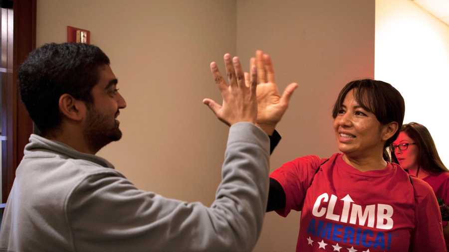 Vinayak Sinha (left), a "ClimbCorps" member, gives Dina Martinez a high five when she arrives at the finish point.
