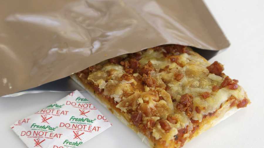 A slice of prototype pizza, in development to be used in MRE's — meals ready to eat, sits in a packet next to a smaller packet known as an oxygen scavenger, left, at the U.S. Army Natick Soldier Research, Development and Engineering Center.