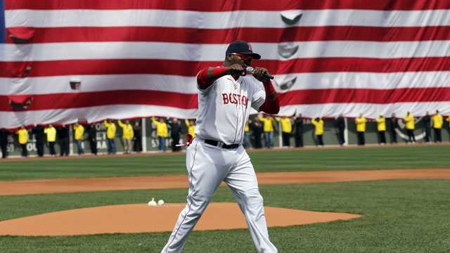 Boston Red Sox's David Ortiz pumps his fist in front of an Amarican flag and a line of Boston Marathon volunteers, background, after addressing the crowd before a baseball game between the Boston Red Sox and the Kansas City Royals in Boston, Saturday, April 20, 2013.