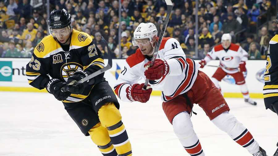 Boston Bruins' Chris Kelly (23) and Carolina Hurricanes' Jordan Staal (11) battle for the puck in the first period of an NHL hockey game in Boston, Saturday, March 15, 2014.