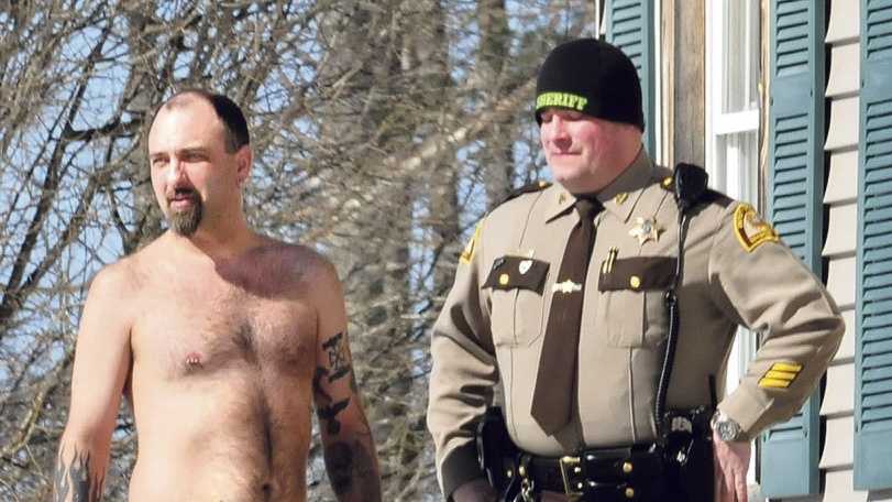 Norridgewock resident Michael Smith stands beside a Somerset County sheriff’s deputy Tuesday morning. The tattoo of a pistol on his stomach was mistaken for a real firearm by employees of Lucas Tree Experts after, according to Smith, workers woke him up while they were cutting wood for Central Maine Power Co. The workers called police. Photo courtesy Morning Sentinel