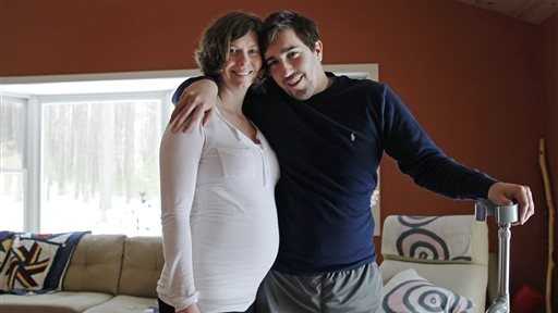 In this March 14, 2014 photo, Jeff Bauman, who lost both his legs above the knee in the Boston Marathon bombing, poses with his fiancee Erin Hurley at their Carlisle, Mass., home. The couple are expecting their first child in July.