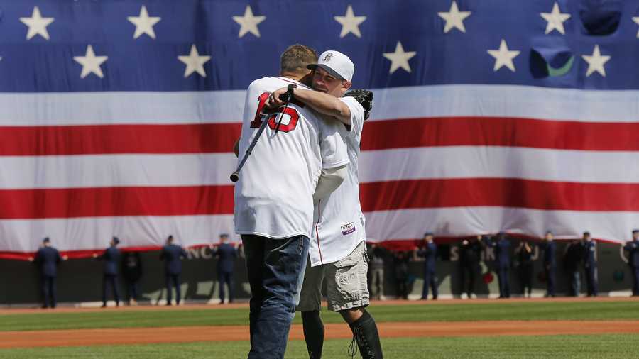 Boston Marathon bombing survivor Marc Fucarile hugs former Red Sox player Kevin Millar after throwing out the ceremonial first pitch before the baseball game between the Boston Red Sox and the Baltimore Orioles at Fenway Park in Boston Monday, April 21, 2014.