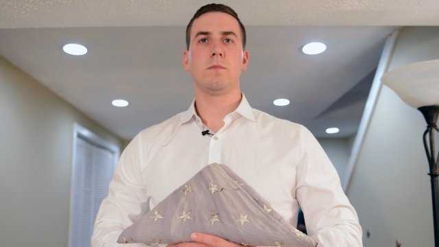 In his home in New Hampshire, May 3, 2014, Ryan Pitts, who is to receive the Medal of Honor for combat actions in Afghanistan, holds the flag that his grandfather flew every day while Pitts served in the Army.