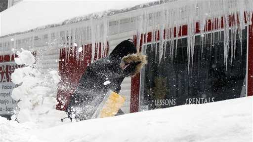 Corbit Larson clears snow in front of icicles hanging off his Centre Music store, Monday, Feb. 9, 2015, in Framingham, Mass. 