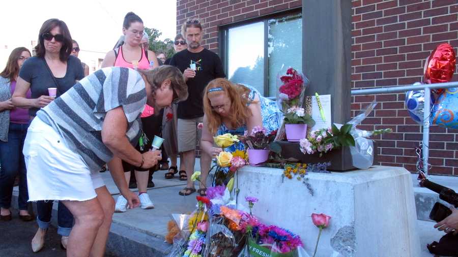 People place flowers, Sunday, Aug. 9, 2015, at the site where Vermont social worker Lara Sobel was killed on Friday in Barre, Vt. About 300 people attended a vigil that began at a labor hall and ended at the site where Sobel was shot Friday as she left work. Jody Herring, the woman charged with Sobel's death, is due in court Monday.