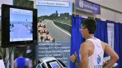 Joe Ciavattone, an employee of Outside Interactive, demonstrates the company's virtual race technology at the New Balance Falmouth Road Race expo in Falmouth, Mass. The company is partnering with the race to let runners compete on a treadmill virtually from anywhere while watching video footage of the actual 7-mile course.