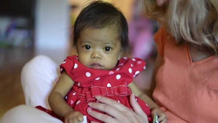 Hope Morrison, 17-Months, looks around while siting in adoptive mother, Cindy's, lap at their home in Andover.