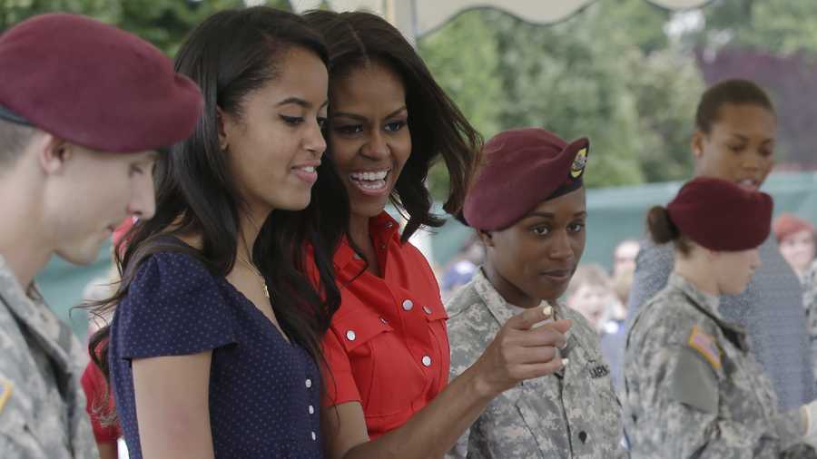 U.S. first lady Michelle Obama shares a light moment with her daughter Malia as they serve ice cream to children during a meeting with soldiers and their families at the U.S. Army Garrison Vicenza, northern Italy, Friday, June 19, 2015.