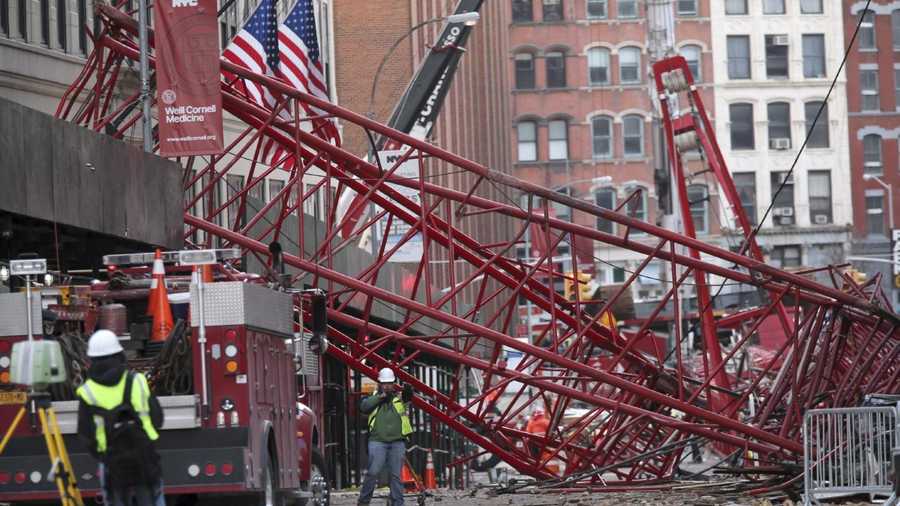 Firefighters and construction crews work on clearing a collapsed crane, Saturday, Feb. 6, 2016, in New York. Officials are working to determine why a huge construction crane that was being lowered during strong winds came crashing down onto a street. 