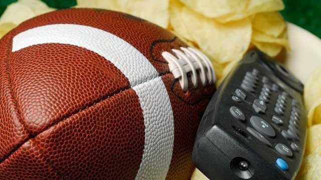 A photo of a football with a TV remote and potato chips