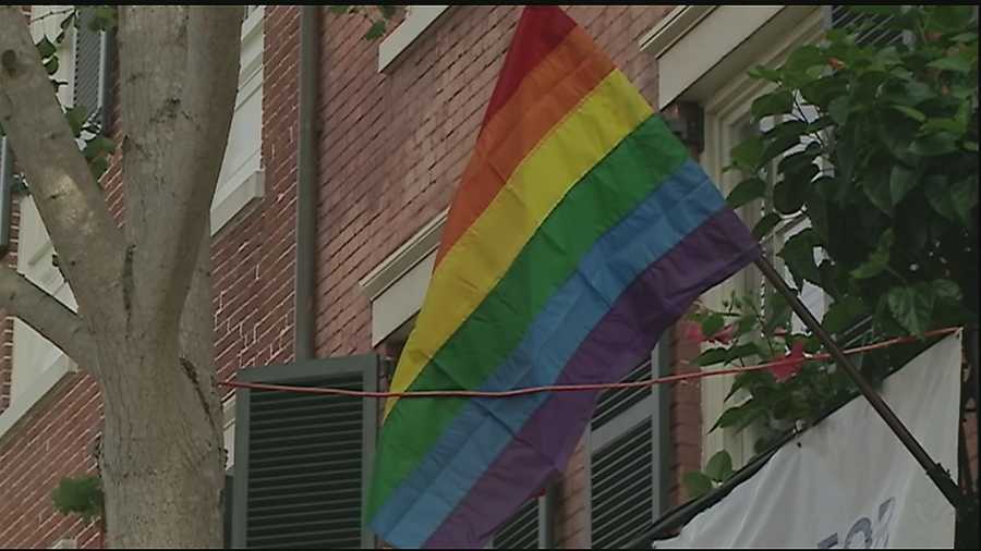 A man is caught on surveillance video tearing down a gay pride flag and spray painting a derogatory term on the building's shutters.