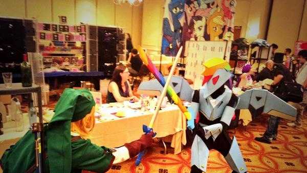 A photo of Link from "The Legend of Zelda" series clashes swords with Laura Ducros, who is clad in an armored version of Rainbow Dash.