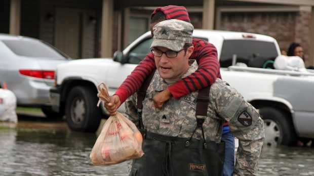 Sgt. Jason C. Carroll, electronic warfare specialist with the Louisiana National Guard's 528th Engineer Battalion, 225th Engineer Brigade, carries a young resident through flooded streets in Monroe, Louisiana, March 10, 2016. The 528th used high-water vehicles, in cooperation with the Ouachita Parish Sheriff's Office, to navigate high waters to assist evacuating residents.
