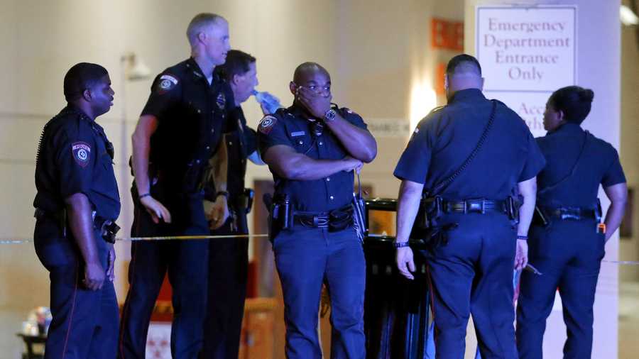 A Dallas police officer covers his face as he stands with others outside the emergency room at Baylor University Medical Center, Friday, July 8, 2016, in Dallas. Snipers opened fire on police officers in the heart of Dallas on Thursday night, killing some of the officers.