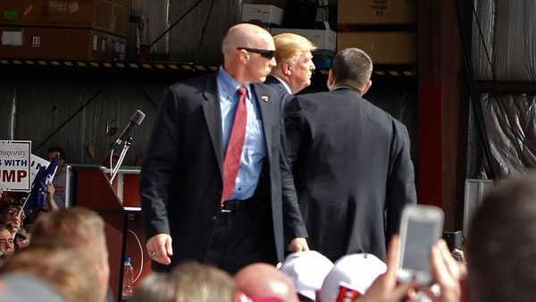 Secret Service agents guard Republican presidential candidate, businessman Donald Trump, on the stage after a man tried to breach the security buffer at his campaign event at the Wright Brothers Aero Hangar Saturday, March 12, 2016, in Vandalia, Ohio.