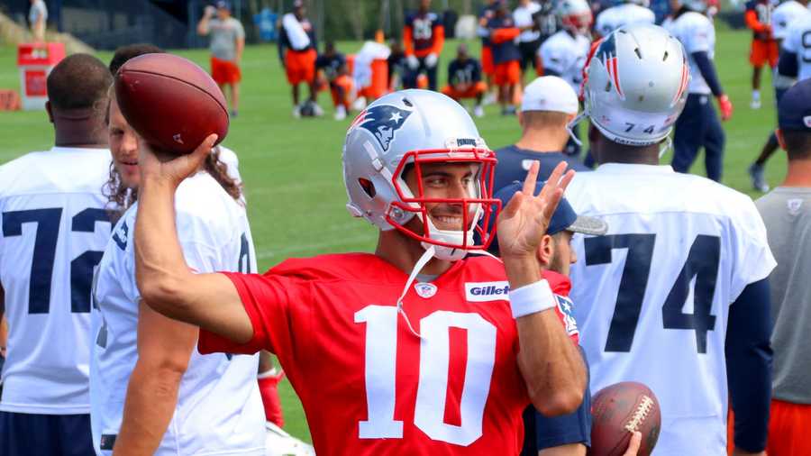 Patriots quarterback Jimmy Garoppolo tosses passes on the sidelines while the defense works on the field. 