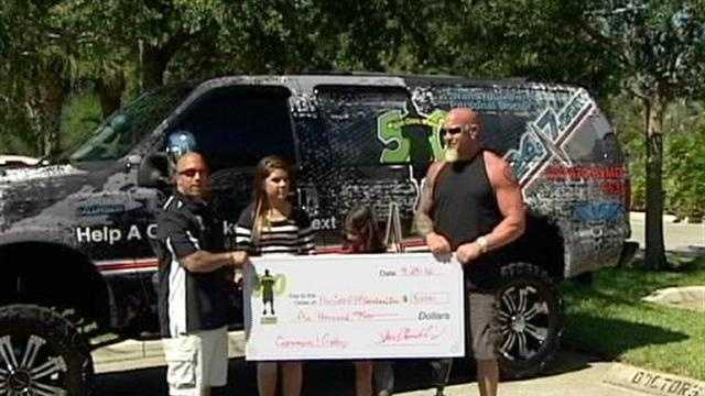Pro wrestler Steve Chamberland donates a $5,000 check to help pay for two girls' prosthetic legs.