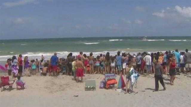 Beachgoers try to help a teenager who was swept under the water by a wave at John U. Lloyd Beach State Park.