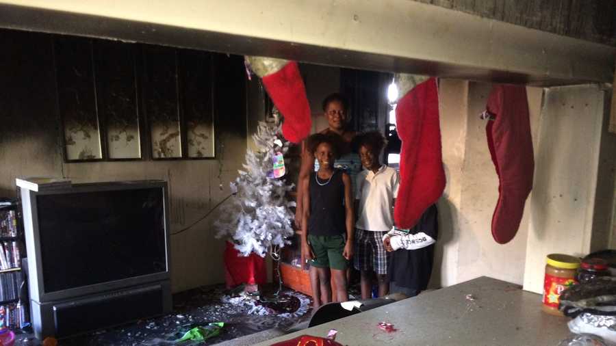 Demetrius Wynter and her grandchildren stand inside their house, which was damaged in a fire two days before Christmas.