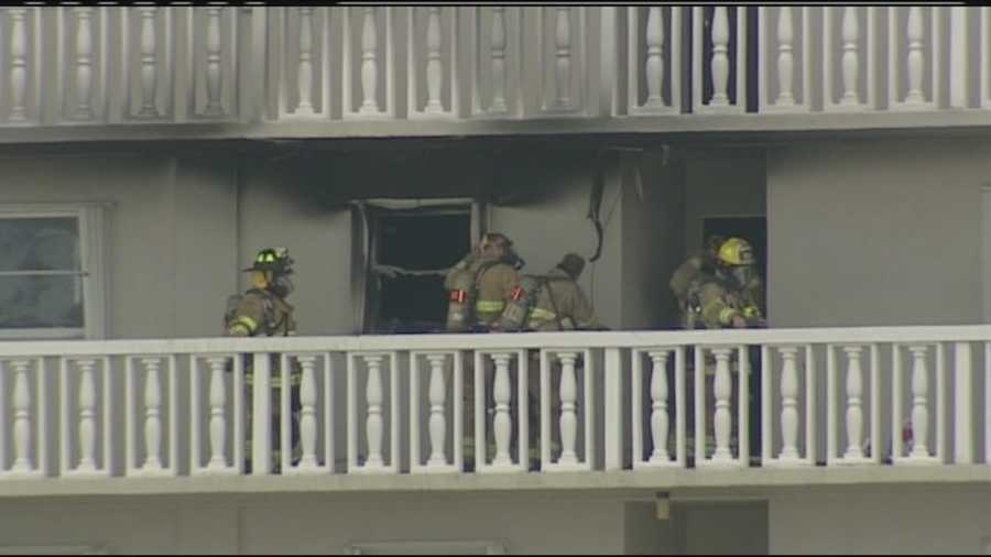 Firefighters work to clean up after flames damaged a vacant unit at this Lake Park high-rise condo.