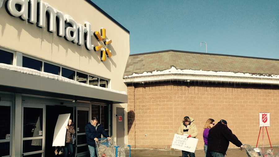 Barry Kade of Montgomery hands leaflets to shoppers deriding Walmart's employee wages and benefits outside the Berlin, VT store Friday.