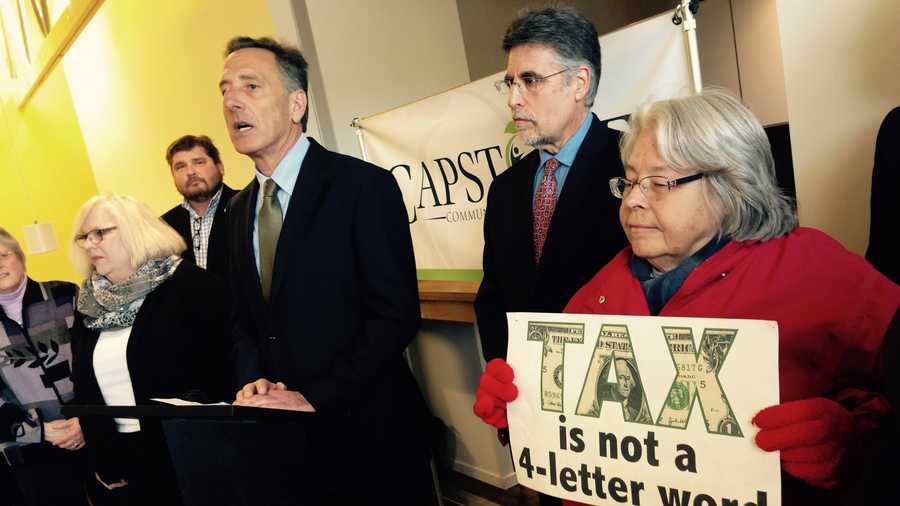 Gov. Shumlin speaks at a Barre news conference Tuesday as Alexandra Thayer, right, stands in silent protest over his budget and tax policies.  