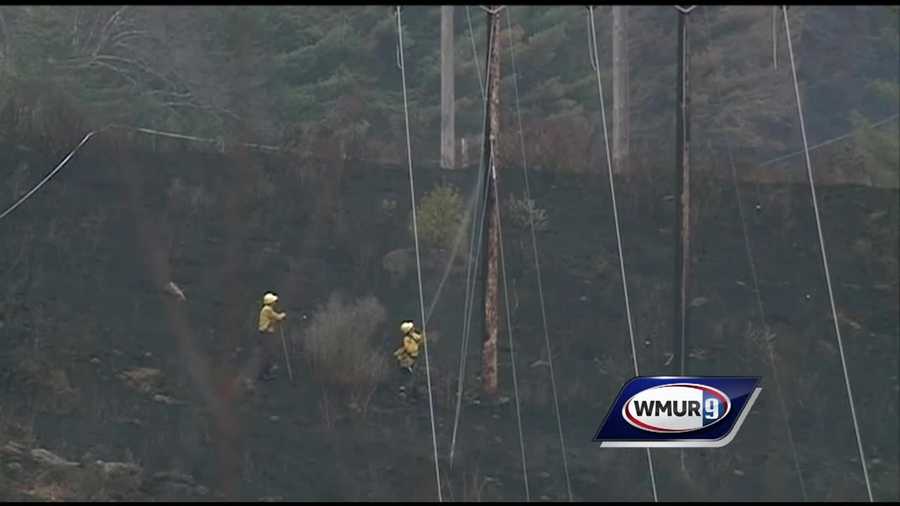 Firefighters spray water onto utility poles as they work to contain a massive brush fire in Stoddard.