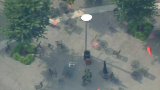 A bomb squad officer approaches a red suitcase that was reported as a suspicious package in Market Square.