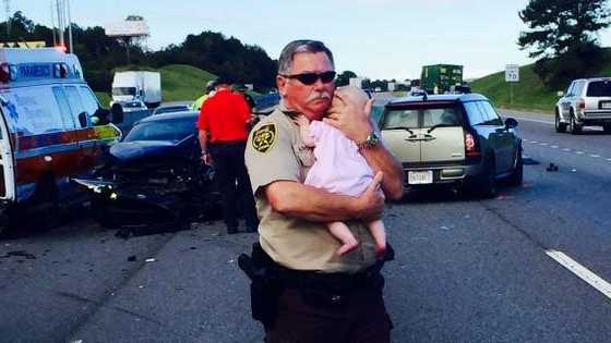 Jefferson County Sheriff's Deputy Ric Lindley cradles an infant on the scene of a wreck near Leeds Tuesday morning. 