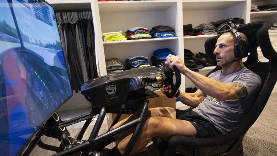 IndyCar driver Tony Kanaan, of Brazil, practices on his racing simulator in his home in Indianapolis, Saturday, March 28, 2020. Kanaan, along with other IndyCar drivers and NASCAR's Jimmie Johnson will compete in the series' inaugural virtual racing event Saturday. (AP Photo/Michael Conroy)