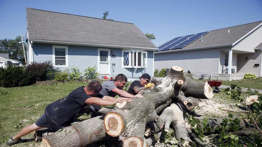 From left to right, Grant Whitmore, Jason Kirk and Peter Delaney roll a tree trunk while cutting it apart at Whitmore's home in northwest Cedar Rapids, Iowa, on Wednesday, Aug. 12, 2020. Straight-line winds on Monday knocked out power, trees and damaged homes and businesses region-wide. (Liz Martin/The Gazette via AP)