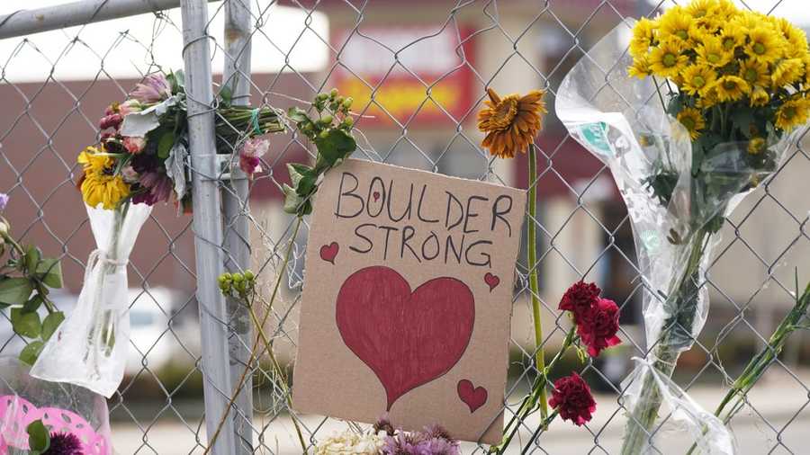 a sign is flanked by floral bouquets placed on the temporary fence put up around the parking lot of a king soopers grocery store thursday, march 25, 2021, in boulder, colo. ten people were killed in a mass shooting at the supermarket on monday. (ap photo/david zalubowski)