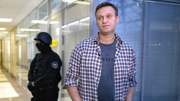 In this Dec. 26, 2019, file photo, Russian opposition leader Alexei Navalny speaks to the media in front of a security officer standing guard at the Foundation for Fighting Corruption office in Moscow, Russia.
