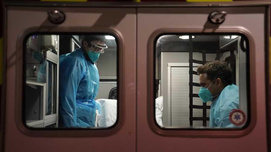 Emergency medical technician Thomas Hoang, left, of Emergency Ambulance Service, and paramedic Trenton Amaro prepare to unload a COVID-19 patient from an ambulance in Placentia, Calif., Friday, Jan. 8, 2021.