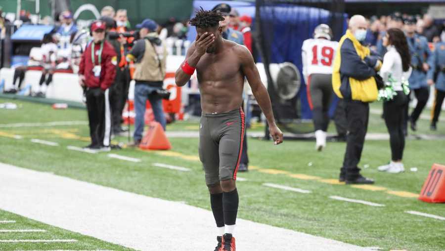 Tampa Bay Buccaneers wide receiver Antonio Brown wipes his face as he leaves the field after throwing his equipment into the stands while his team is on offense during the third quarter of an NFL football game against the New York Jets, Sunday, Jan. 2, 2022, in East Rutherford, N.J.
