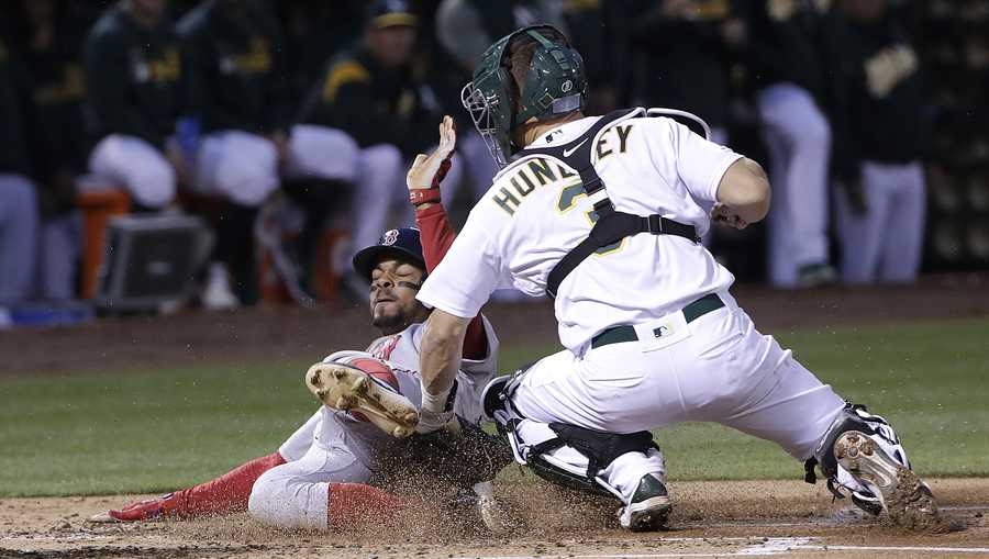 Boston Red Sox' Xander Bogaerts, left, is tagged out at home by Oakland Athletics catcher Nick Hundley during the second inning of a baseball game in Oakland, Calif., Monday, April 1, 2019. (AP Photo/Jeff Chiu)