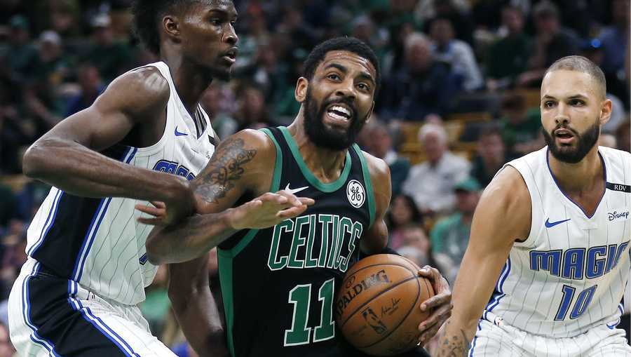 Boston Celtics' Kyrie Irving (11) drives for the basket between Orlando Magic's Evan Fournier (10) and Jonathan Isaac during the first half of an NBA basketball game in Boston, Sunday, April 7, 2019. (AP Photo/Michael Dwyer)