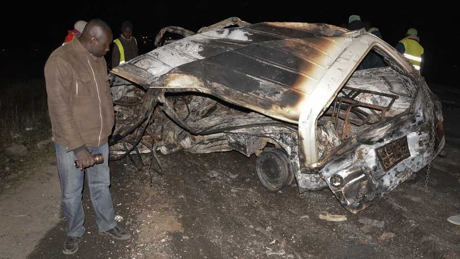 A man looks at the wreckage of a passenger minibus following an accident near Naivasha, Kenya Sunday, Dec. 11, 2017. A tanker carrying chemical gas slammed into other vehicles and burst into flames on a major road in Kenya, officials said Sunday.