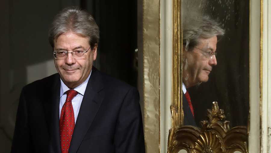 Italian Premier Paolo Gentiloni is mirrored at right as he arrives with Colombian President Juan Manuel Santos to give a press conference following their meeting at Chigi Palace, in Rome, Friday, Dec. 16, 2016. 
